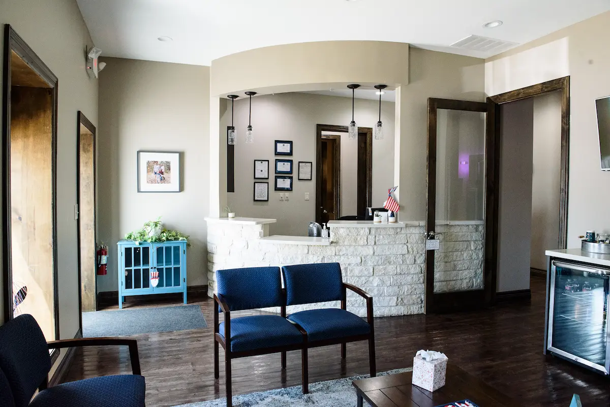 Modern dental office waiting area with comfortable seating, framed credentials, and a clean, inviting reception desk—reflecting professionalism and patient-centered care